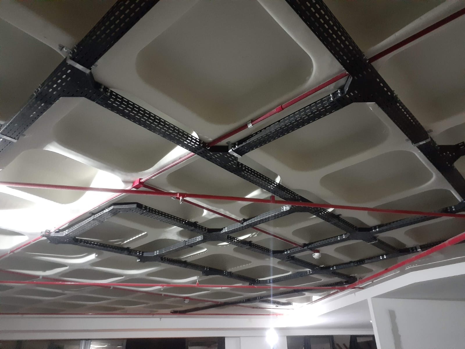 Infraestrutura aparente distribuída no teto de um ambiente